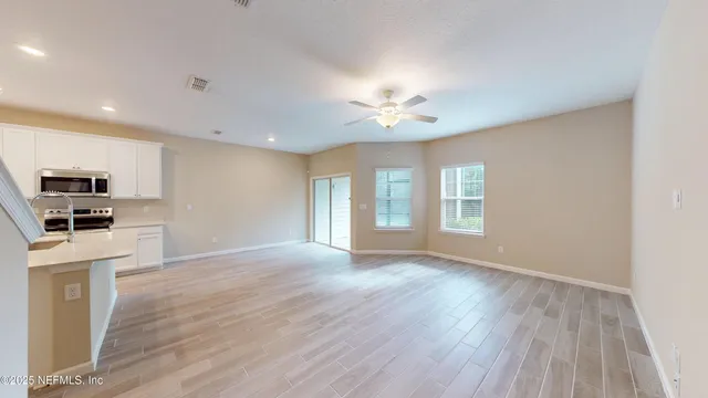 a view of an empty room with a window and wooden floor