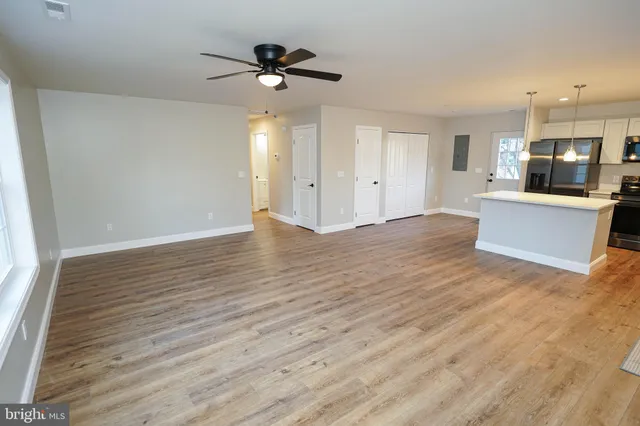 a view of empty room with wooden floor and fan