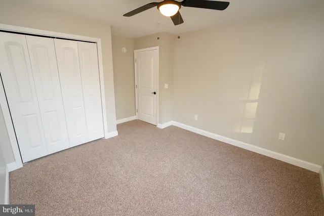 an empty room with a window and a fan