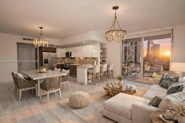 a living room with furniture a chandelier and kitchen view