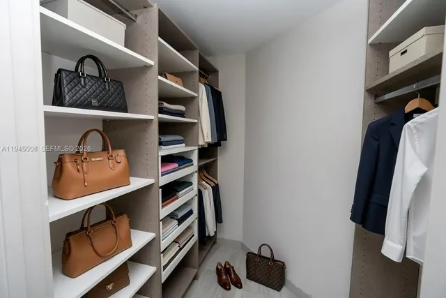 a view of walk in closet with clothes and shoes