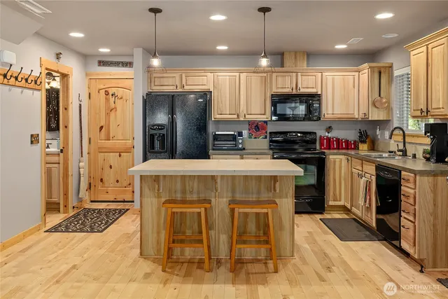 a kitchen with kitchen island granite countertop a stove top oven a sink dishwasher a refrigerator oven and a cabinets with wooden floor