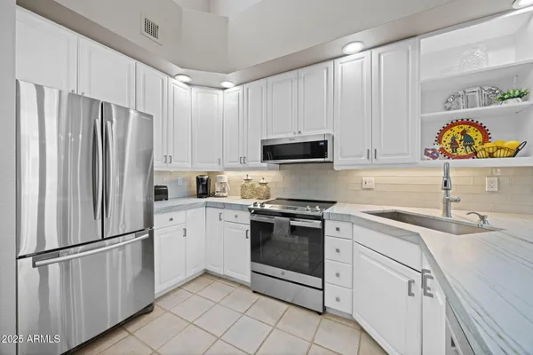 a kitchen with stainless steel appliances granite countertop a refrigerator sink and stove