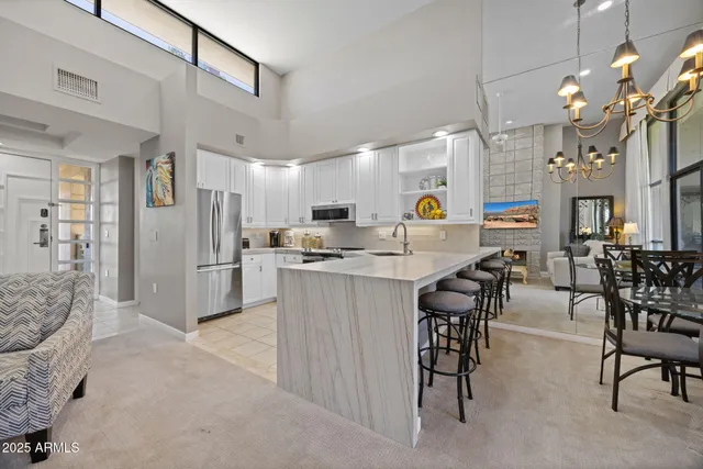 a kitchen with stainless steel appliances kitchen island granite countertop a refrigerator a stove a dining table and chairs with wooden floor