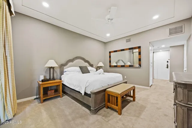 a spacious bedroom with a bed and a flat tv screen on wall