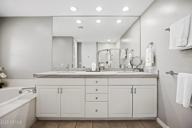 a bathroom with a double vanity sink a mirror and a bathtub