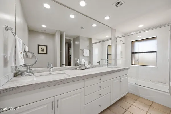 a bathroom with double sink a large mirror and a shower