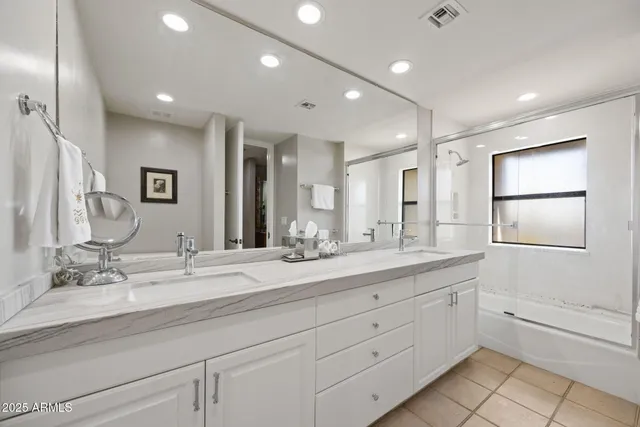 a bathroom with double sink a large mirror and a shower