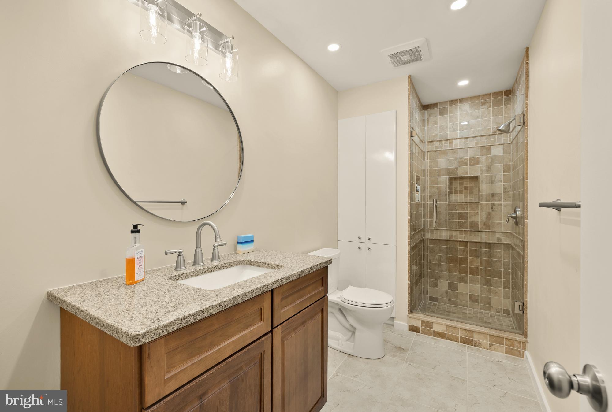 10419 Crossing Creek Road Potomac, MD 20854 - Photo 50 of 74 a bathroom with a granite countertop sink a toilet and a mirror