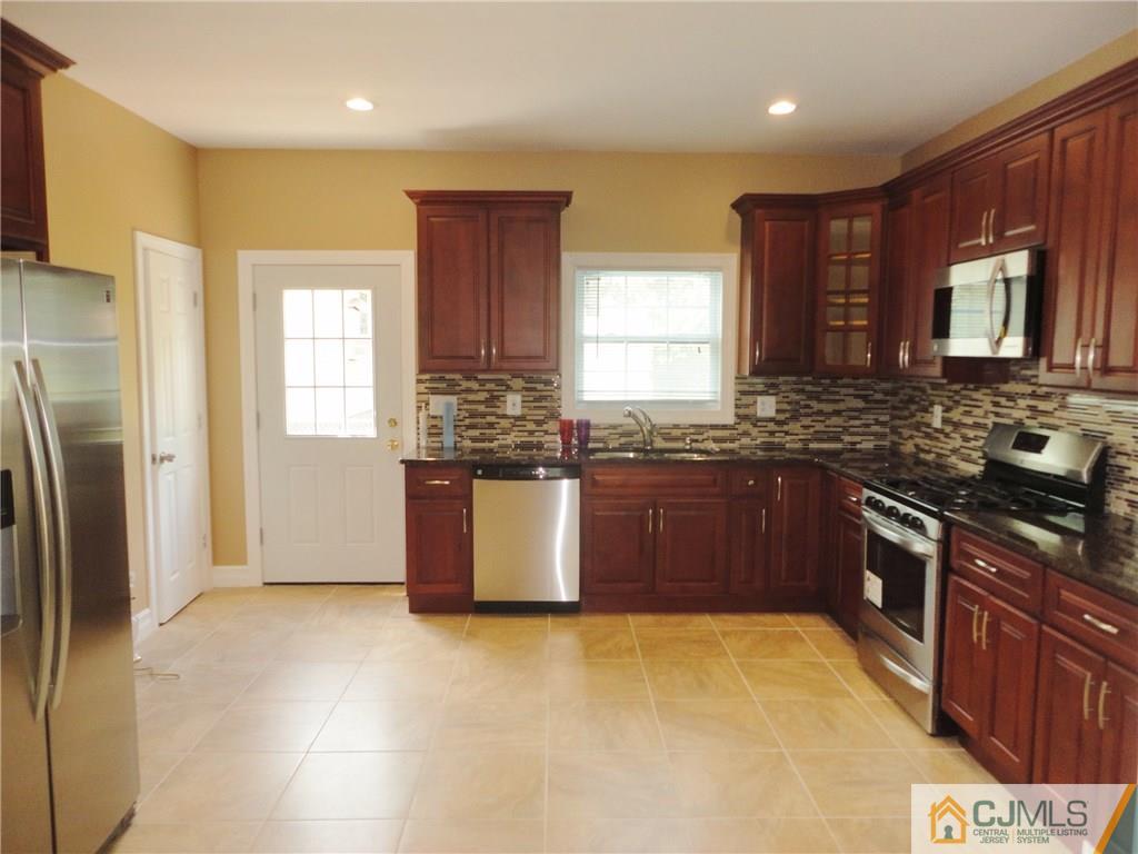 715 Spruce Road North Brunswick, NJ 08902 - Photo 7 of 23 a large kitchen with stainless steel appliances granite countertop a stove a sink dishwasher a refrigerator and wooden cabinets