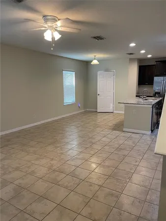 a view of a livingroom with a chandelier fan and kitchen view