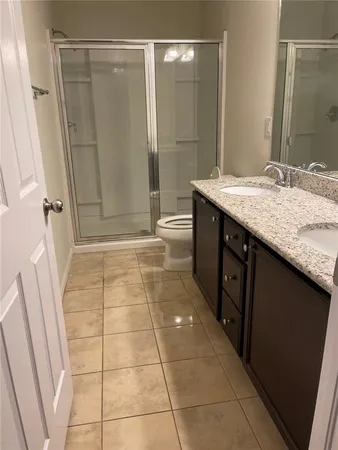 a bathroom with a granite countertop sink a toilet and shower