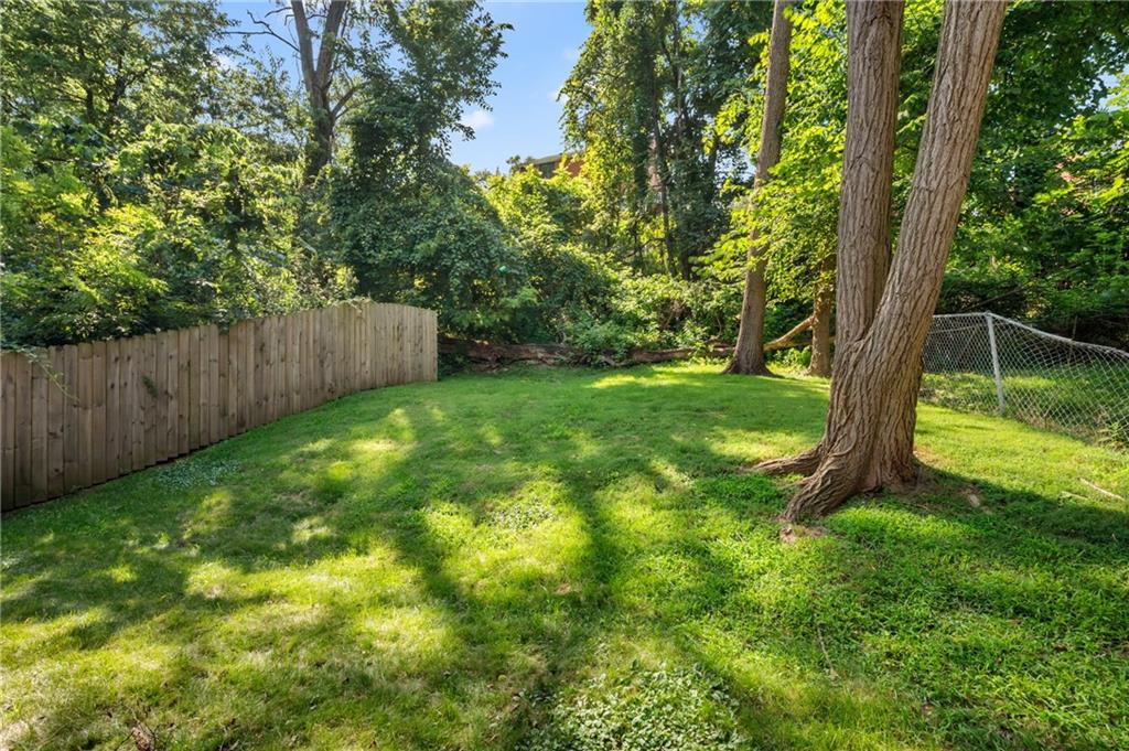 1627-1629 Laketon Road Pittsburgh, PA 15221 - Photo 5 of 26 a view of a backyard with large trees and wooden fence