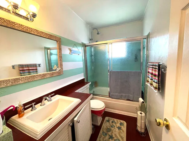 a bathroom with a sink a toilet a mirror and shower