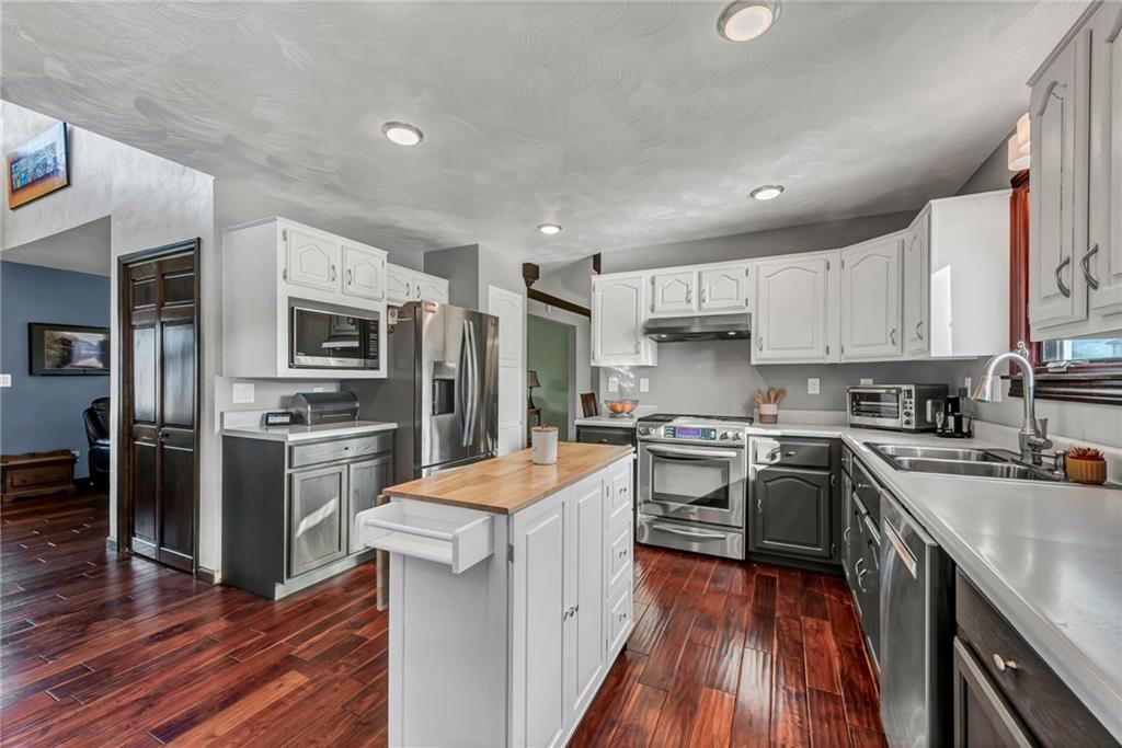 144 Wetzel Road Sarver, PA 16055 - Photo 27 of 48 a kitchen with stainless steel appliances granite countertop a stove top oven a refrigerator a sink and dishwasher with wooden floor