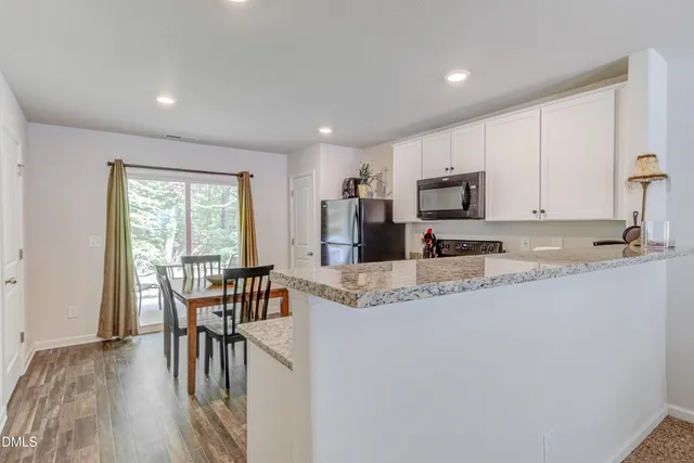 a kitchen with stainless steel appliances granite countertop a stove a sink a refrigerator with a dining table and chairs