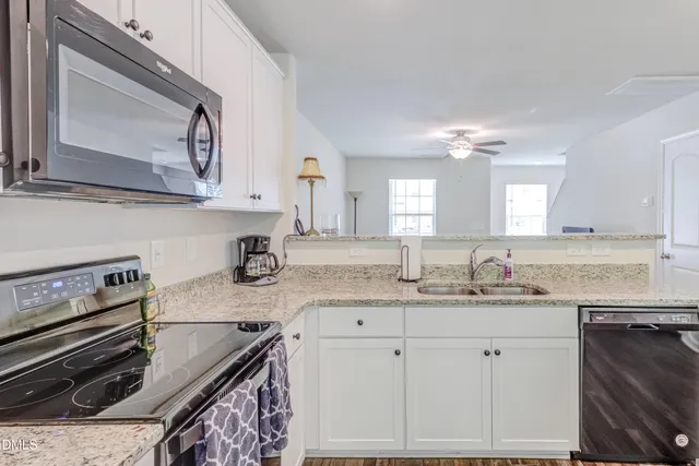a kitchen with granite countertop a sink a stove and cabinets