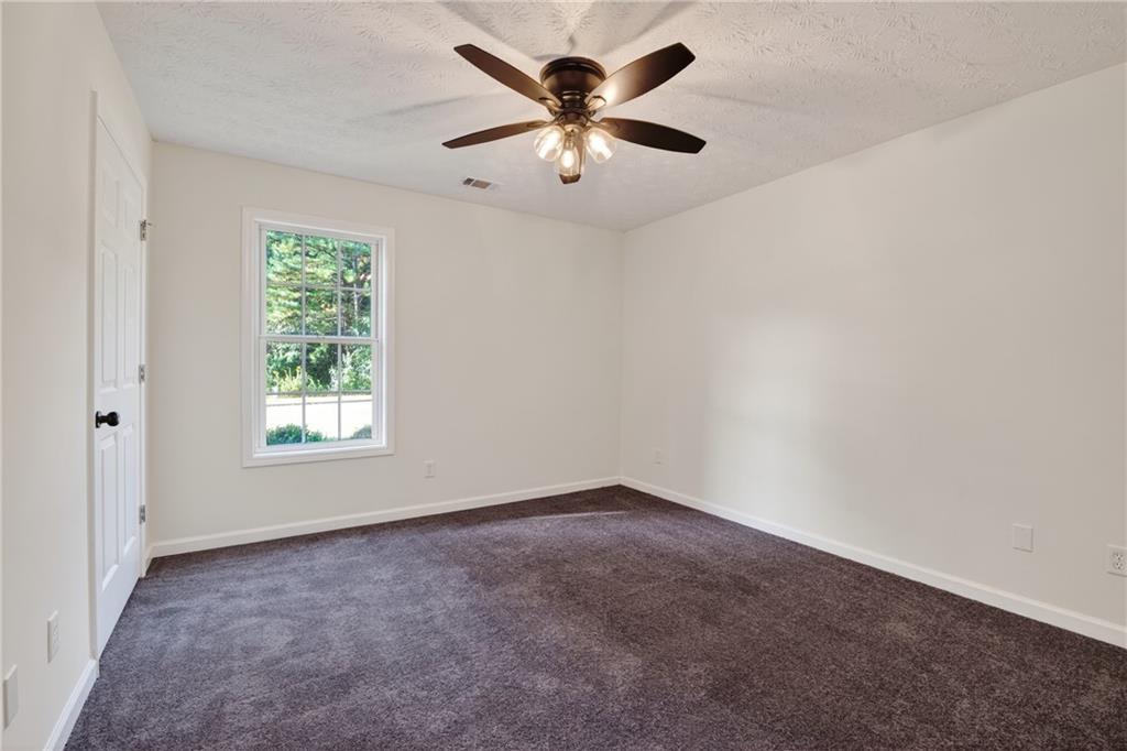 110 Chestnut Drive Covington, GA 30016 - Photo 22 of 27 an empty room with windows and chandelier fan