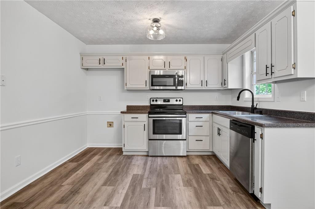 110 Chestnut Drive Covington, GA 30016 - Photo 5 of 27 a kitchen with stainless steel appliances granite countertop a stove a sink and white cabinets