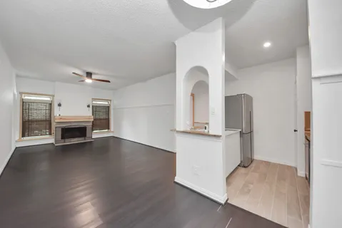 an empty room with wooden floor fireplace and windows