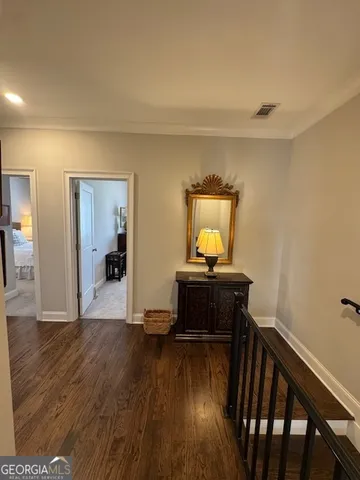 a view of a hallway to a livingroom with wooden floor and furniture