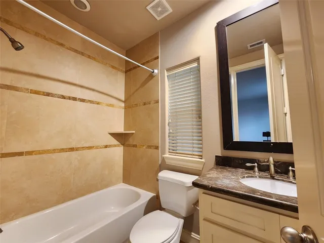 a bathroom with a granite countertop sink mirror vanity and toilet