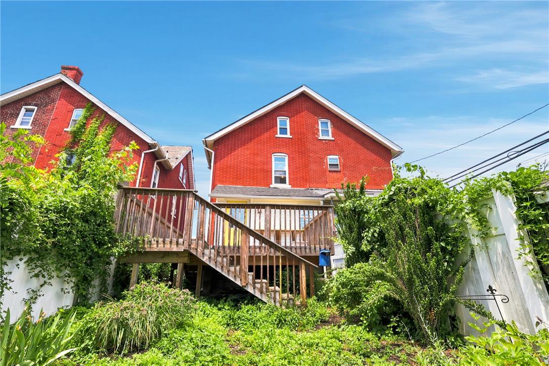 803 Spring Street Bethlehem, PA 18018 - Photo 32 of 34 A tiered wood deck overlooks a lush, green yard with brick homes nestled under a clear sky.