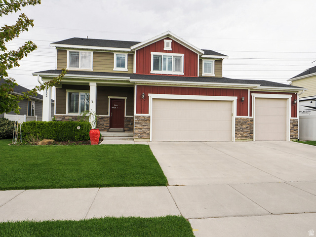 932 Freedom Point Way Bluffdale, UT 84065 - Photo 1 of 1 Craftsman house featuring stone siding, a porch, concrete driveway, board and batten siding, and a front lawn