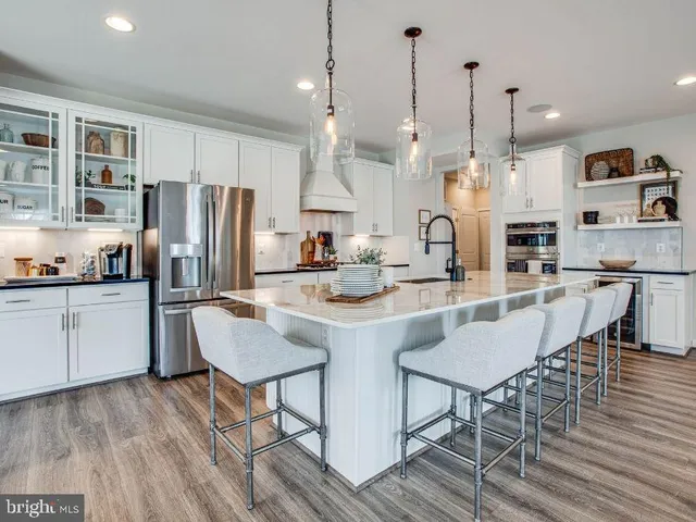 a kitchen with stainless steel appliances kitchen island granite countertop a refrigerator a stove a kitchen island with a dining table and chairs