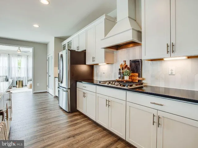 a kitchen with stainless steel appliances a sink dishwasher a refrigerator and cabinets with wooden floor