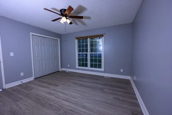 a view of an empty room with window and wooden floor