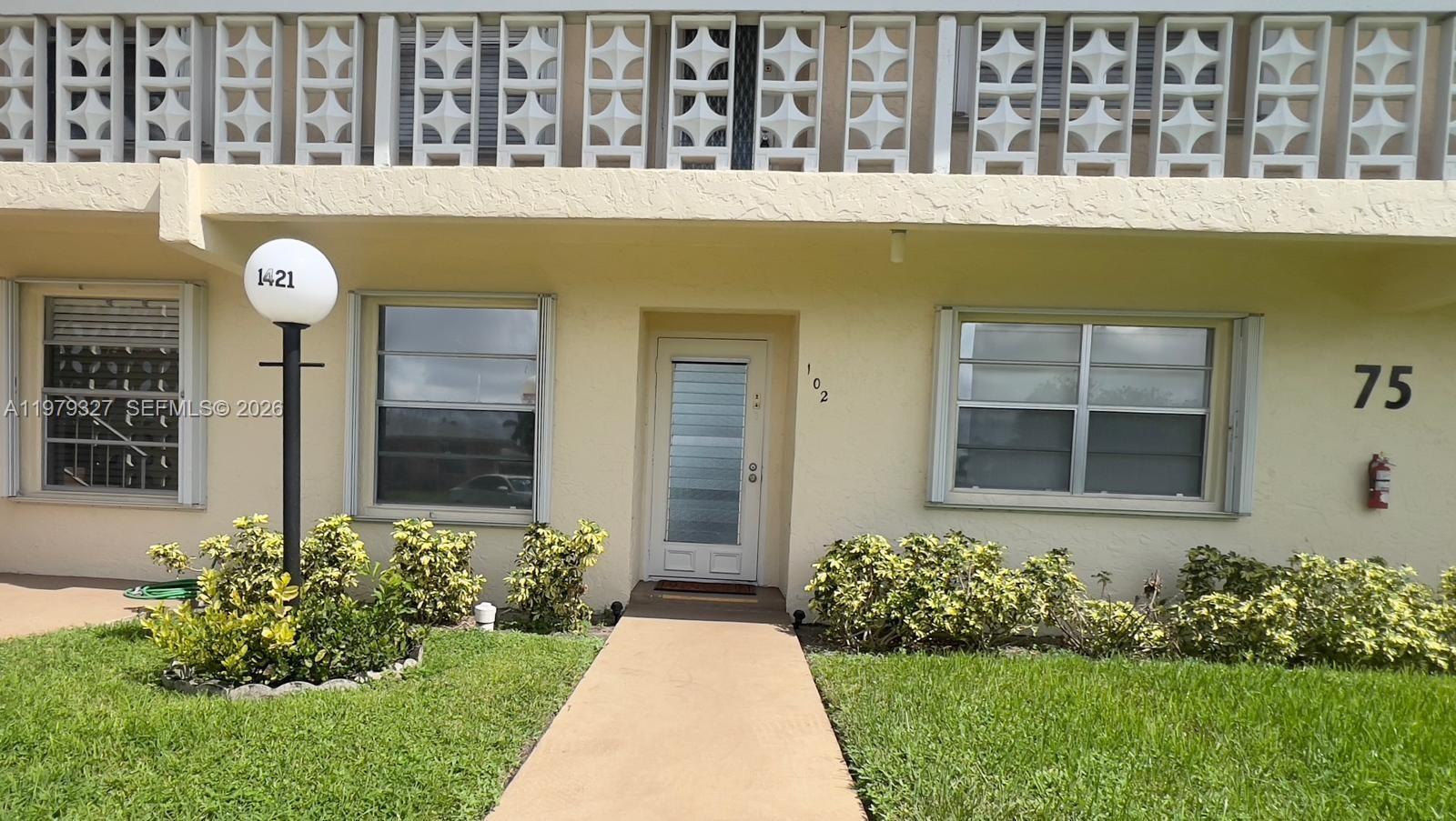 1421 Northwest 19th Terrace, Unit 102 Delray Beach, FL 33445 - Photo 1 of 30 a front view of a house having yard