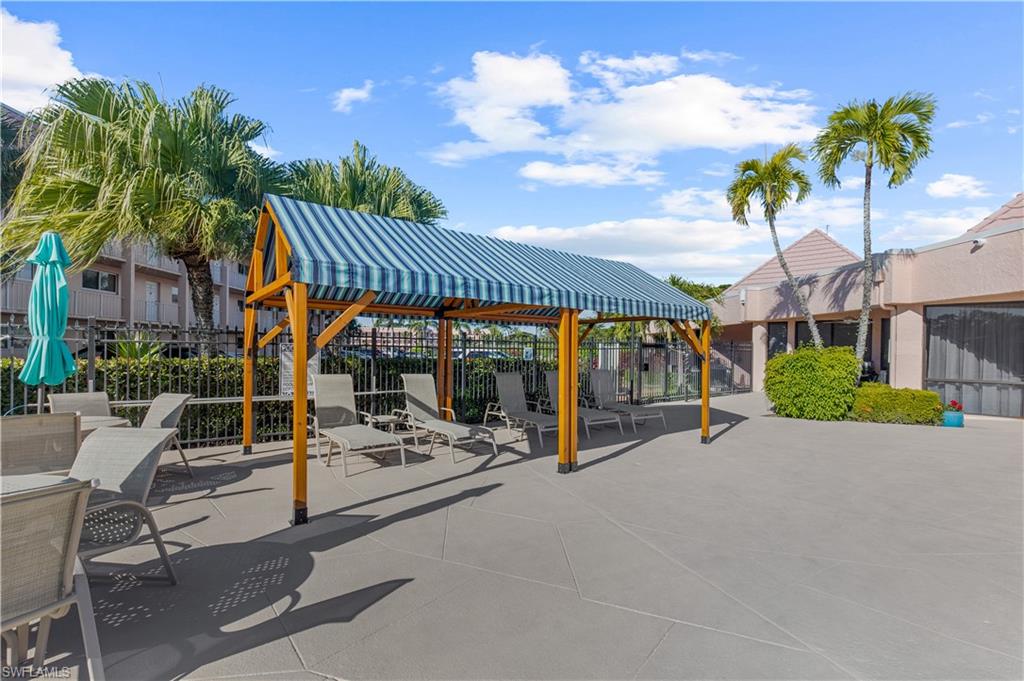 150 Turtle Lake Court, Unit 307 Naples, FL 34105 - Photo 18 of 27 a view of a patio with table and chairs under an umbrella