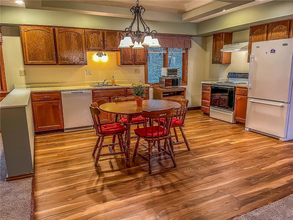 a kitchen with granite countertop a refrigerator a stove a sink dishwasher a dining table and chairs with wooden floor