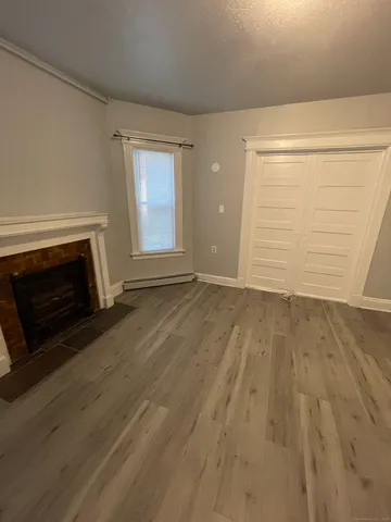 a view of empty room with wooden floor and fireplace