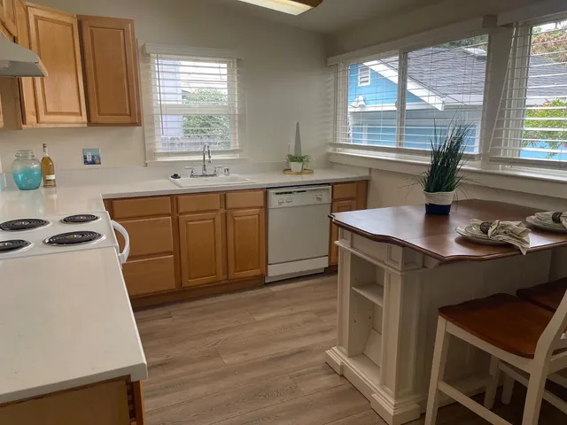 a kitchen with a stove a sink a window and cabinets