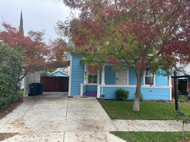 a view of a house with a yard and large tree