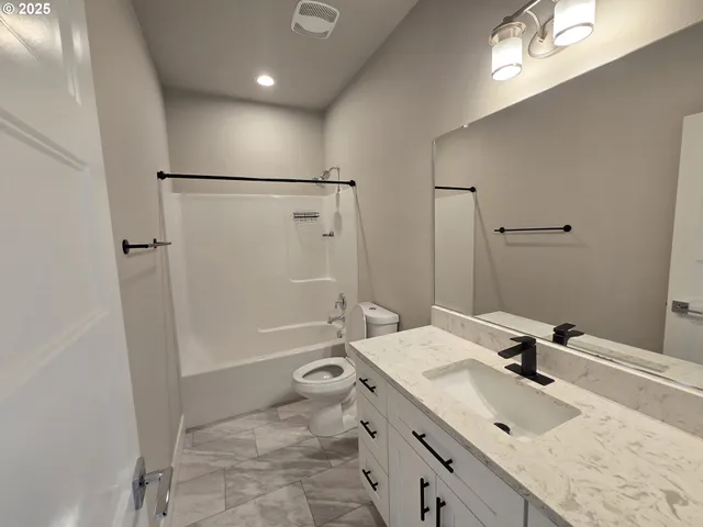 a bathroom with a granite countertop sink a toilet and shower