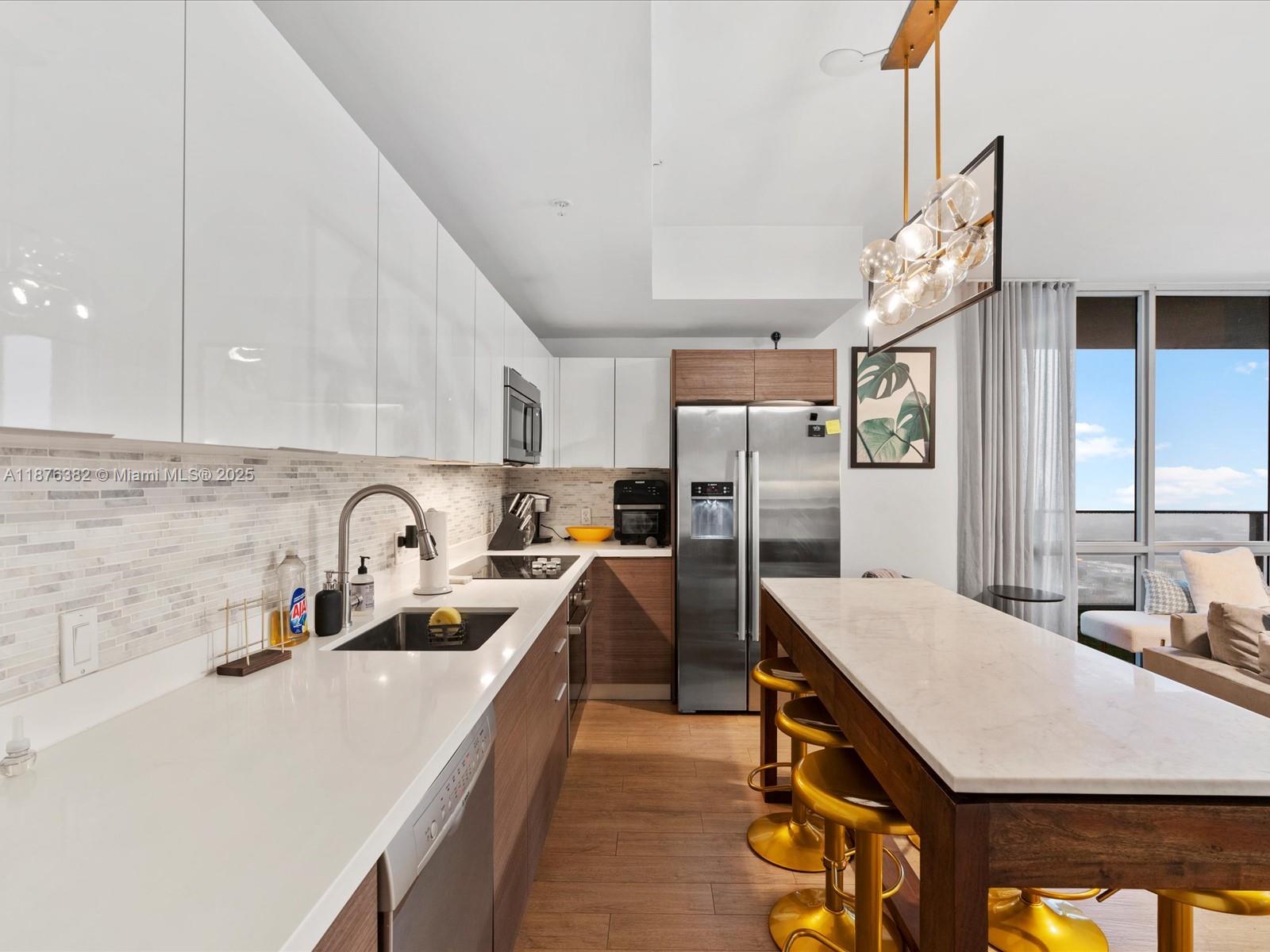 1010 Southwest 2nd Avenue, Unit 1908 Miami, FL 33130 - Photo 6 of 49 a kitchen with stainless steel appliances a sink dishwasher stove refrigerator and cabinets with wooden floor