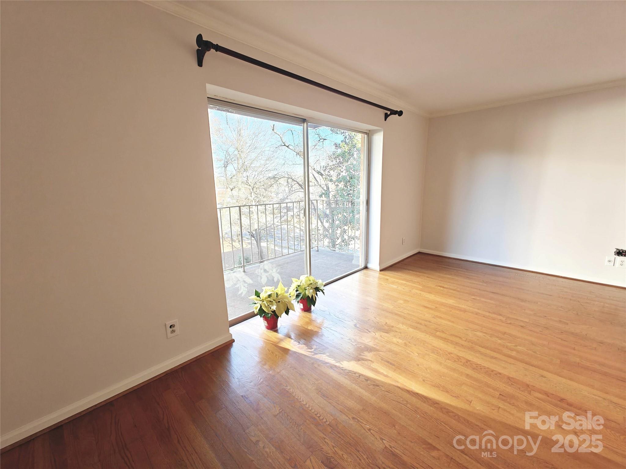 1323 Queens Road, Unit 321 Charlotte, NC 28207 - Photo 4 of 30 a view of an empty room with wooden floor and a window