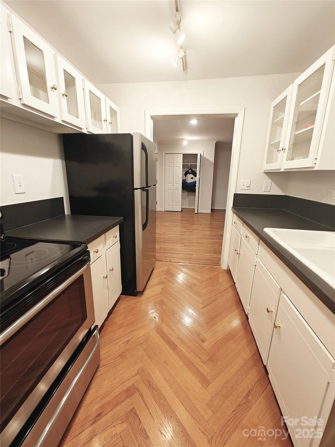 1323 Queens Road, Unit 321 Charlotte, NC 28207 - Photo 9 of 30 a large white kitchen with stainless steel appliances granite countertop a sink and a stove