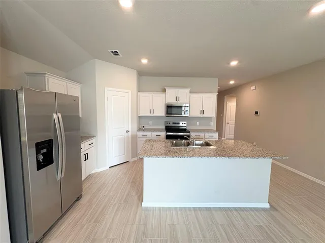 a large kitchen with granite countertop a stove top oven a sink a counter space and cabinets