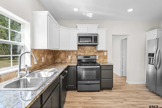 a kitchen with stainless steel appliances granite countertop wooden cabinets a stove top oven a sink and dishwasher