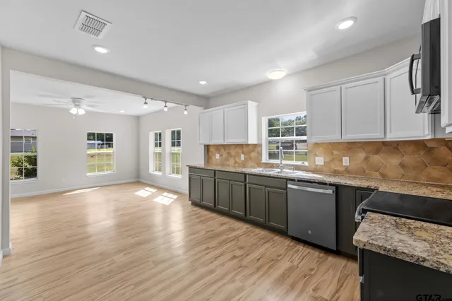 a kitchen with granite countertop white cabinets and a wooden floor