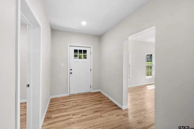 an empty room with wooden floor chandelier fan and windows