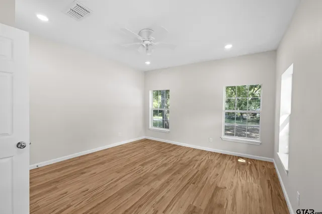 a view of an empty room with wooden floor and a window