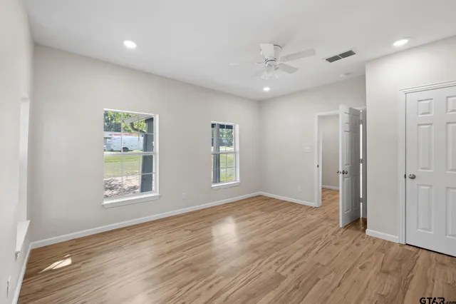 a view of an empty room with a window and wooden floor