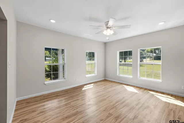 a view of an empty room with kitchen appliances and a ceiling fan