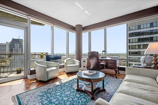 a living room with furniture large windows and wooden floor