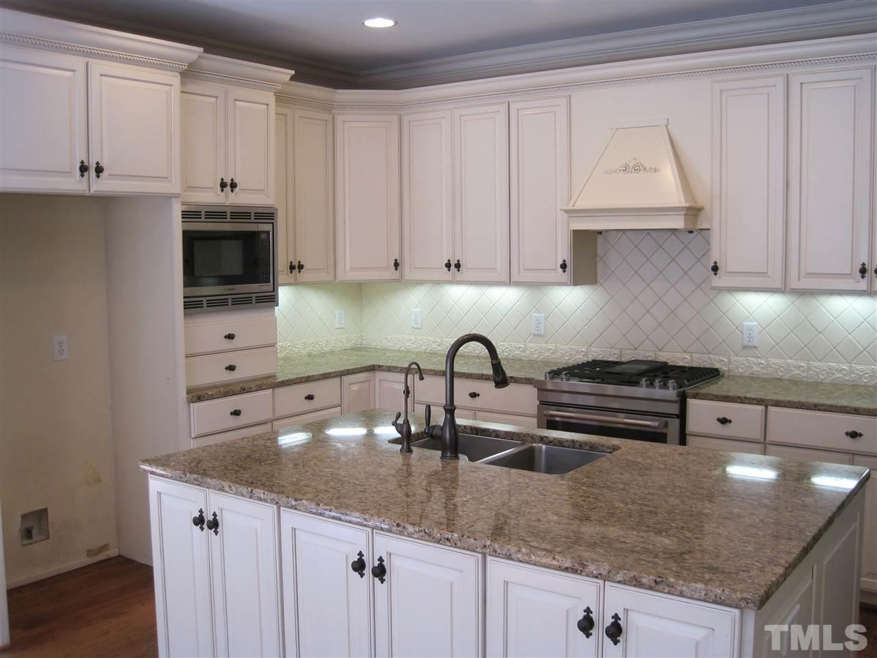 11020 Brass Kettle Road Raleigh, NC 27614 - Photo 7 of 25 Island kitchen with granite tops, tile backsplash, SS gas range/oven, Bosch microwave, dishwasher, bookshelves and desk.